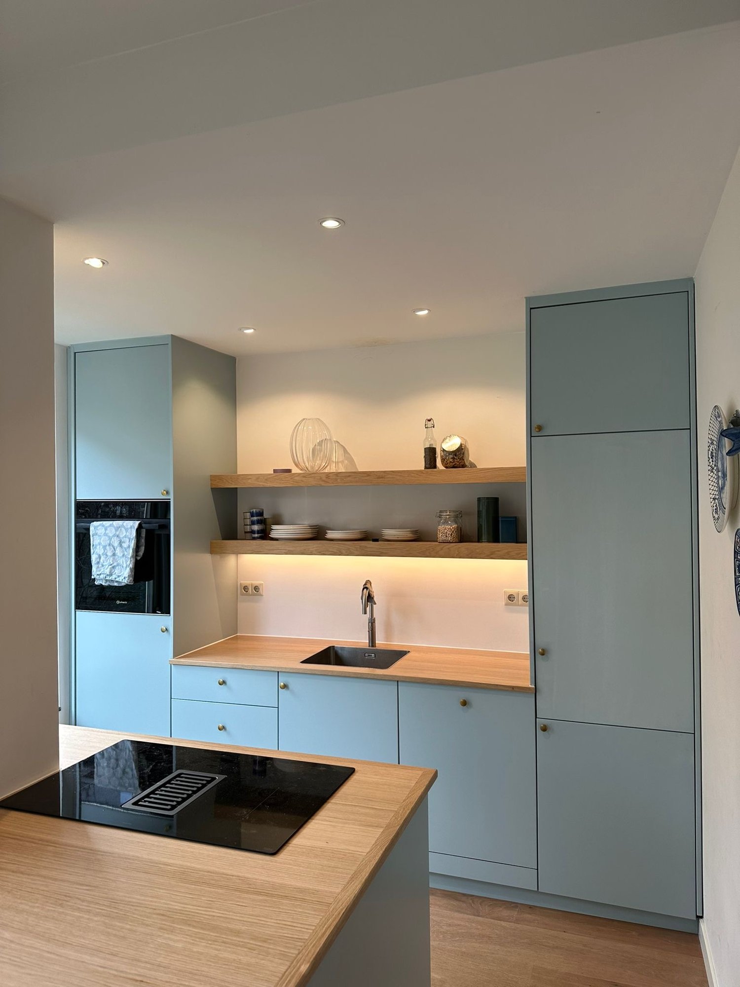 Lichtblauwe keuken met eiken blad en open planken