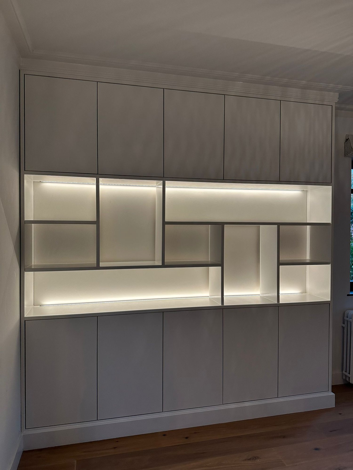 Grijze kastenwand met verlichte vakken