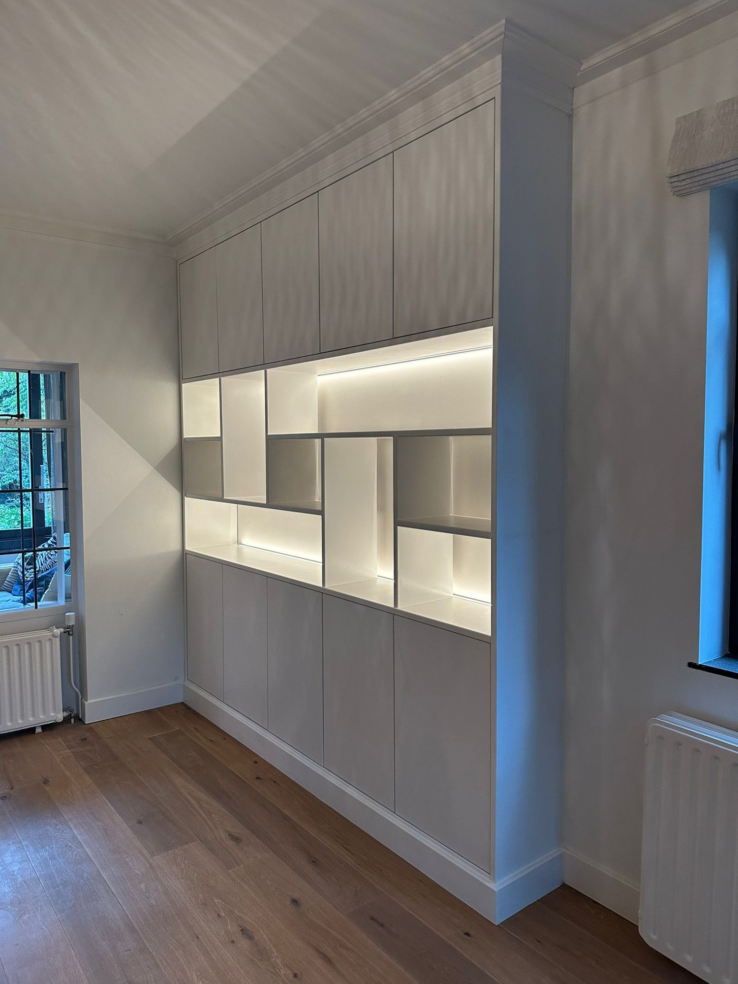 Witte kastenwand met verlichte vakken